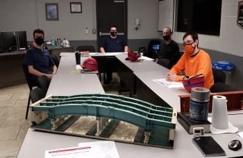 High Steel University coworkers in class studying bridge model.